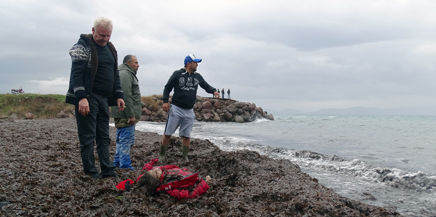 People stand next to the body of a migrant who lies on the shore in the Aegean coastal town of Dikili, near the western city of Izmir, Turkey, on Tuesday (Reuters photo)